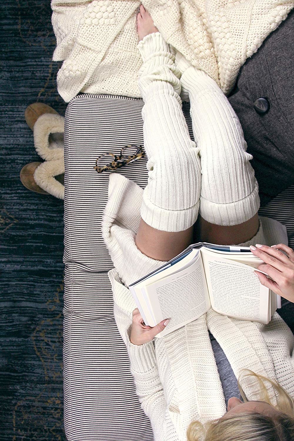 Person reading while wearing leg warmers and a sweater 