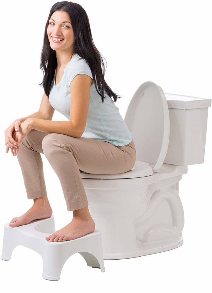 Model sitting on toilet using the squatty potty