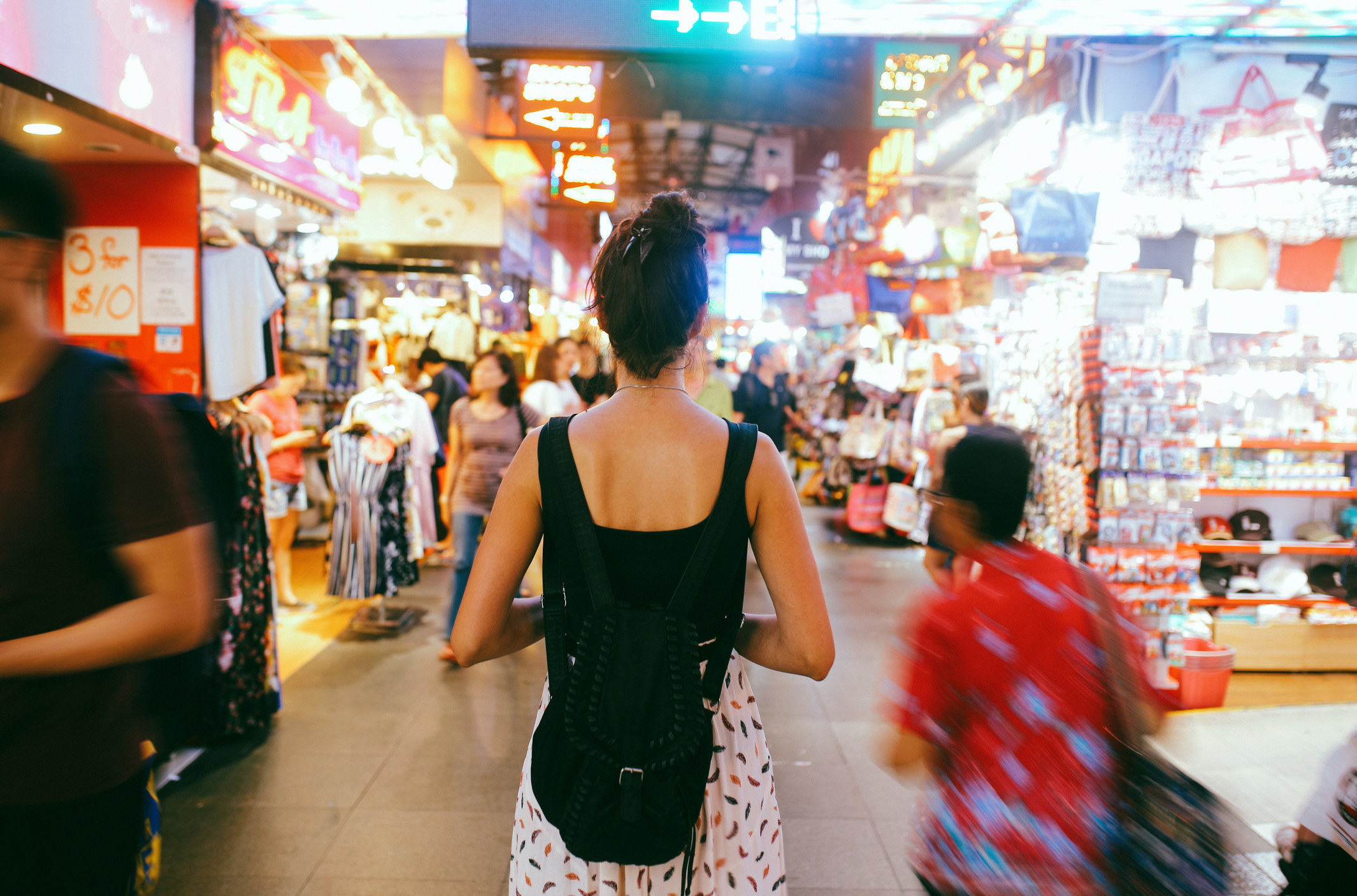 the back of a woman walking through a busy street at night