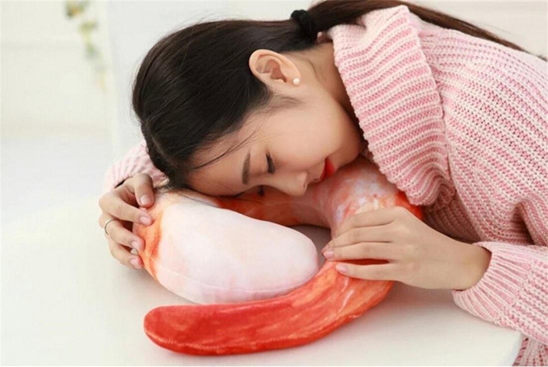 Person resting on the shrimp pillow on a table