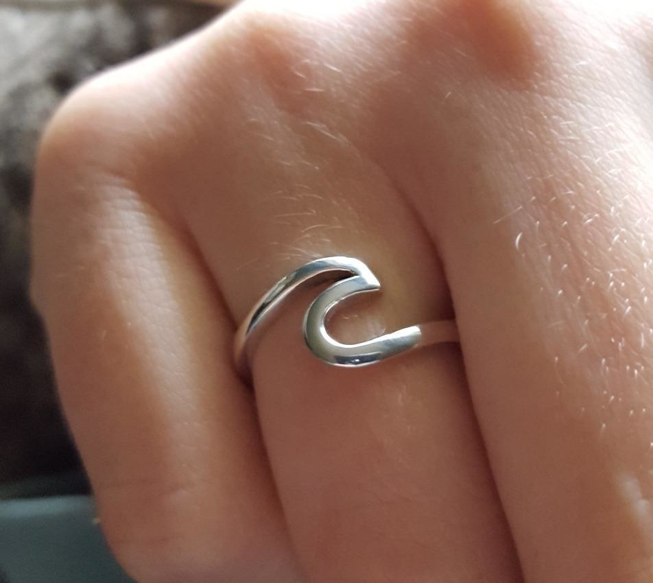 A reviewer showing the silver ring which is the silhouette of a wave