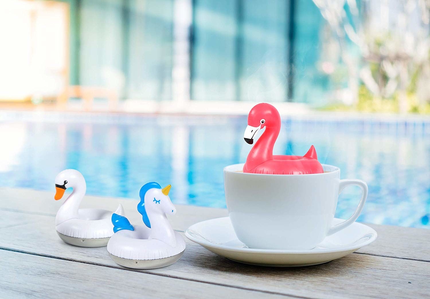 A flamingo diffuser sitting in a cup. There is also a swan diffuser and unicorn diffuser