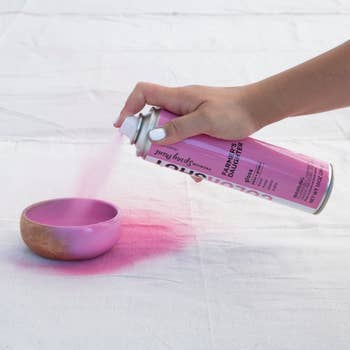 hand using pink spray paint on a dish 