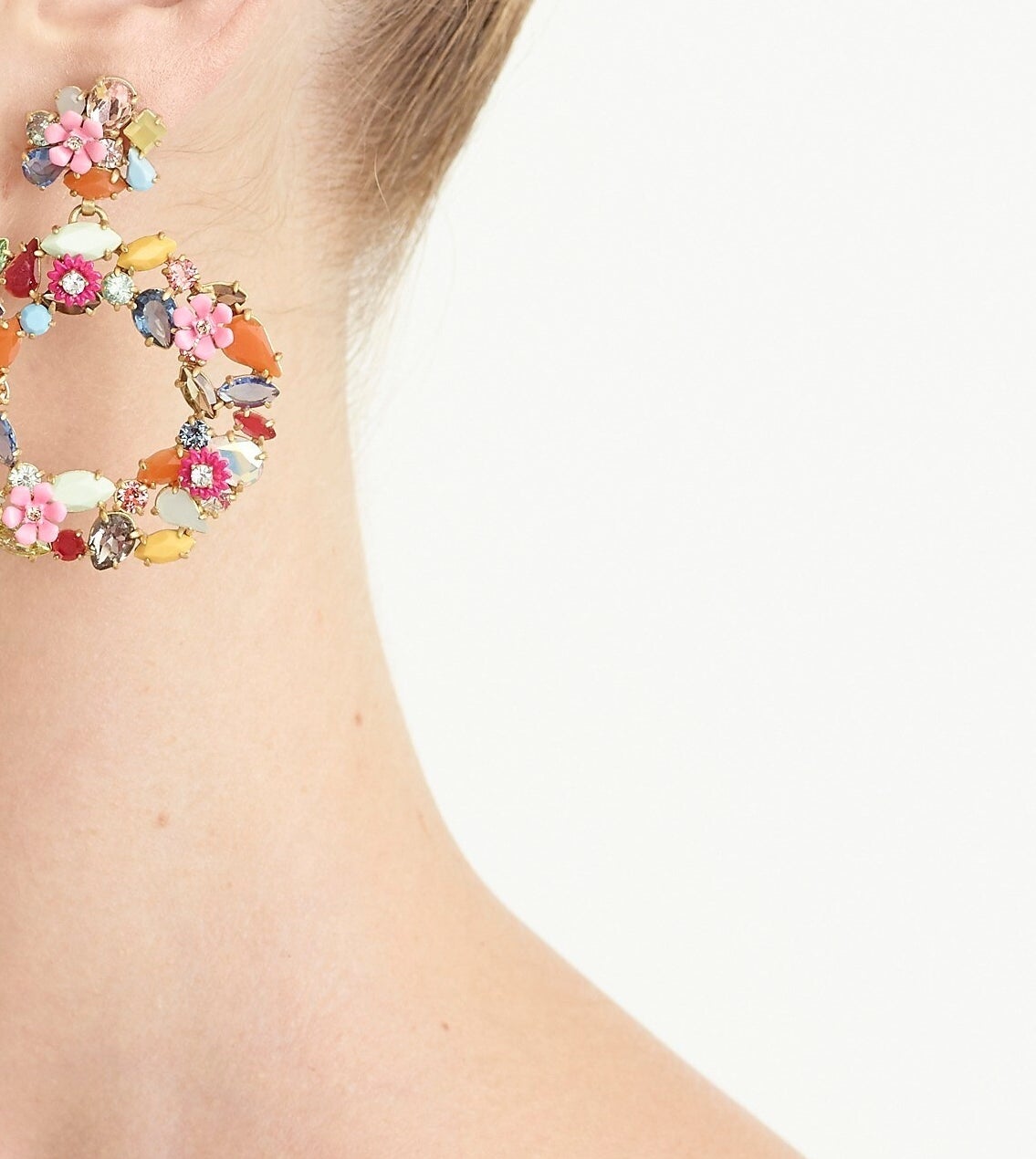 Model wearing the circular stud earrings with different colored stones and flowers