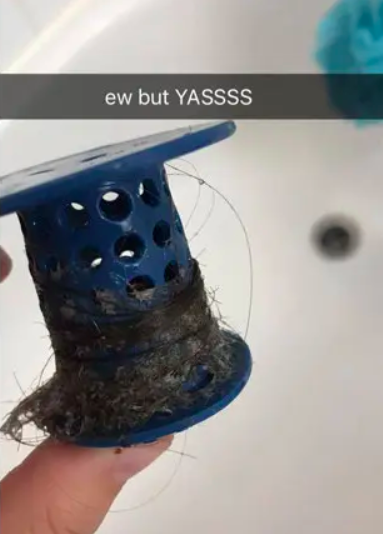 A person holding a cylinder-shaped plug with hair wrapped around it by their bathtub drain There is a caption that says &quot;ew but Yassss&quot;