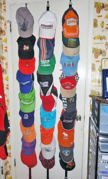 The three-part holder with assorted baseball hats on the back of a door
