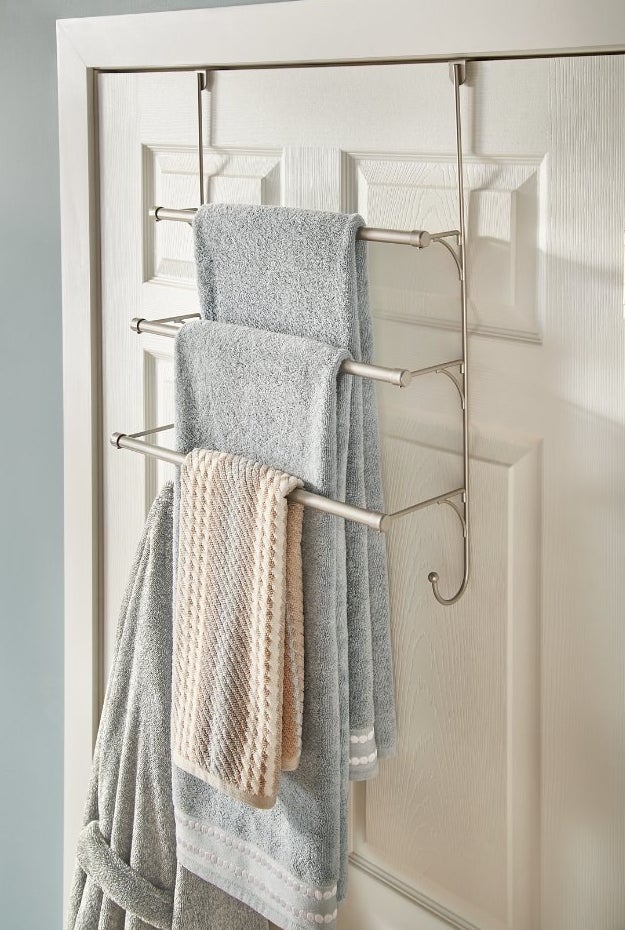 Towel rack hanging over bathroom door holding towels and robe