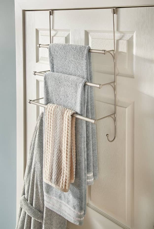 Towel rack hanging over bathroom door holding towels and robe