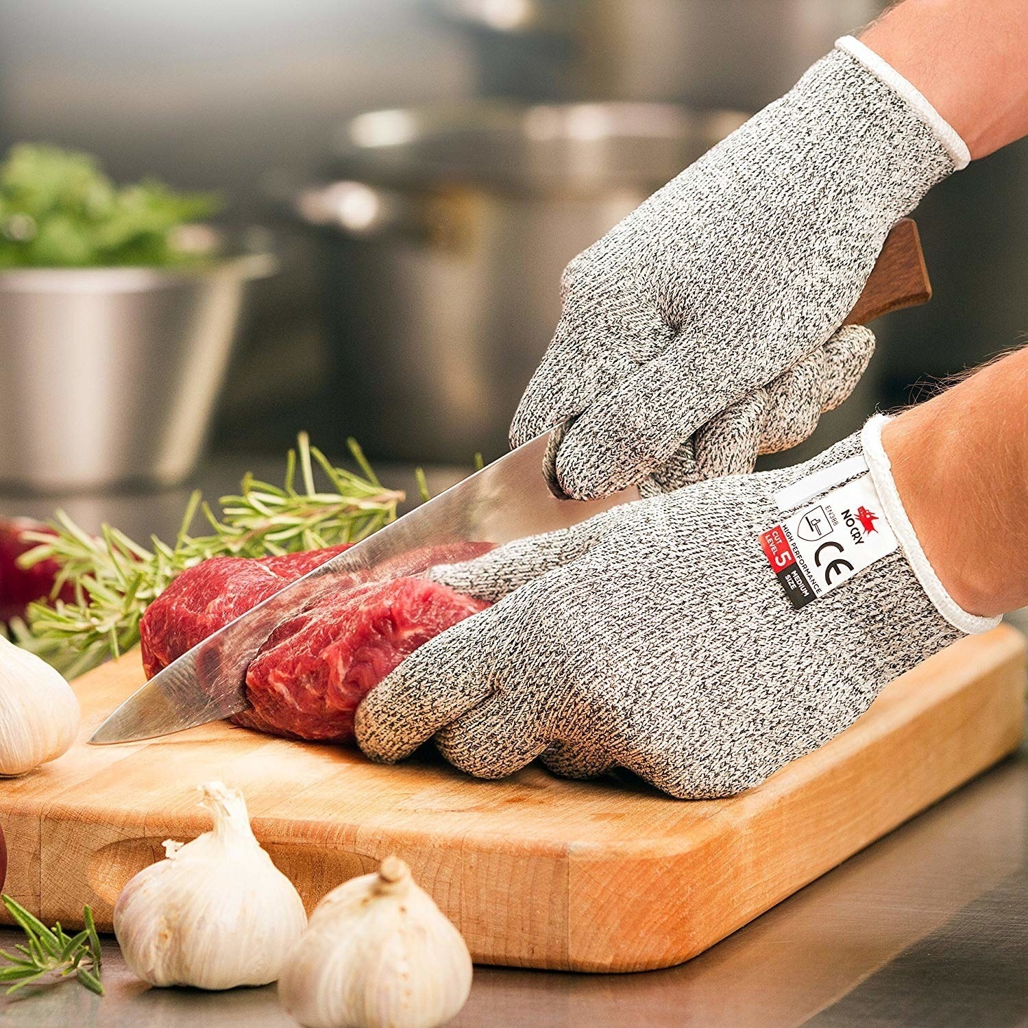 Model wearing gray and white gloves while cutting meat with a knife
