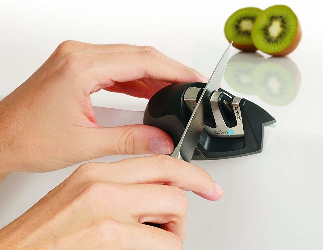 Model holding small black knife sharpener, while sharpening a knife