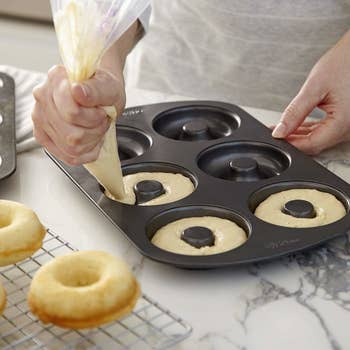a model piping batter into donut molds in the pan