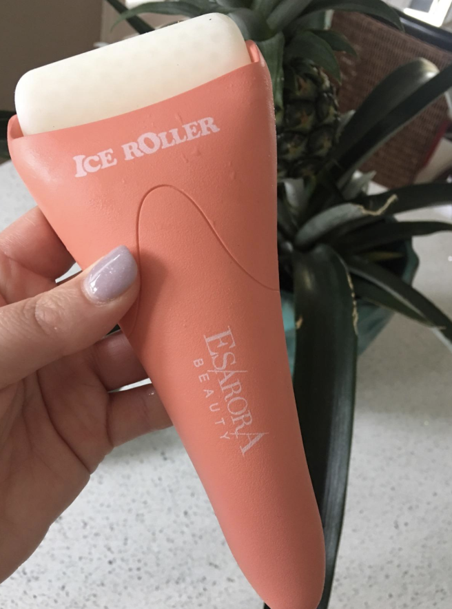 Reviewer holding the ice roller with peach-colored handle and white roller on top