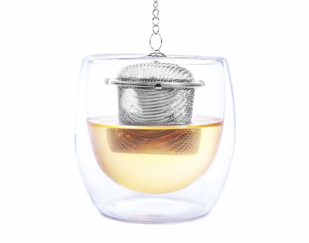 A steel infuser in a cup of tea