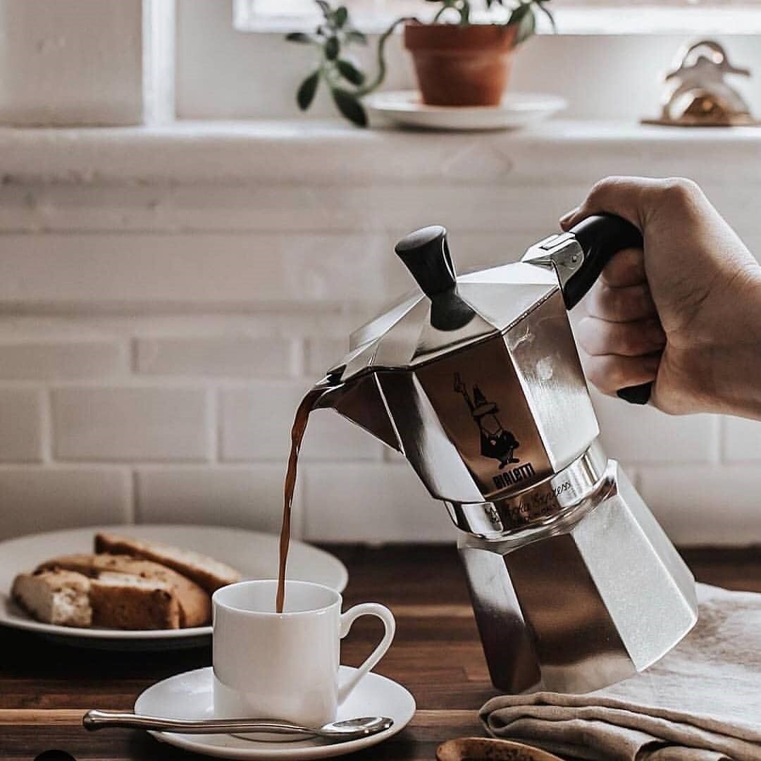 A person using the espresso maker to pour coffee into a mug