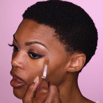 a model applying the shape tape under their eye with an applicator brush