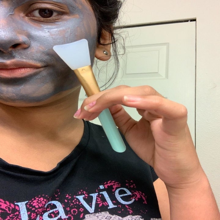 a reviewer using the spatula to apply a mask to her face