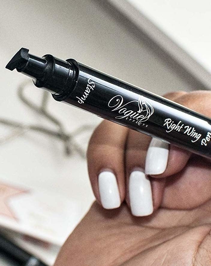 a model holding the black pen with the slanted eyeliner stamp on the end