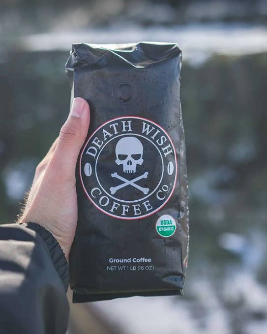 hand holding up the coffee bag with a skull and cross bones design on the bag