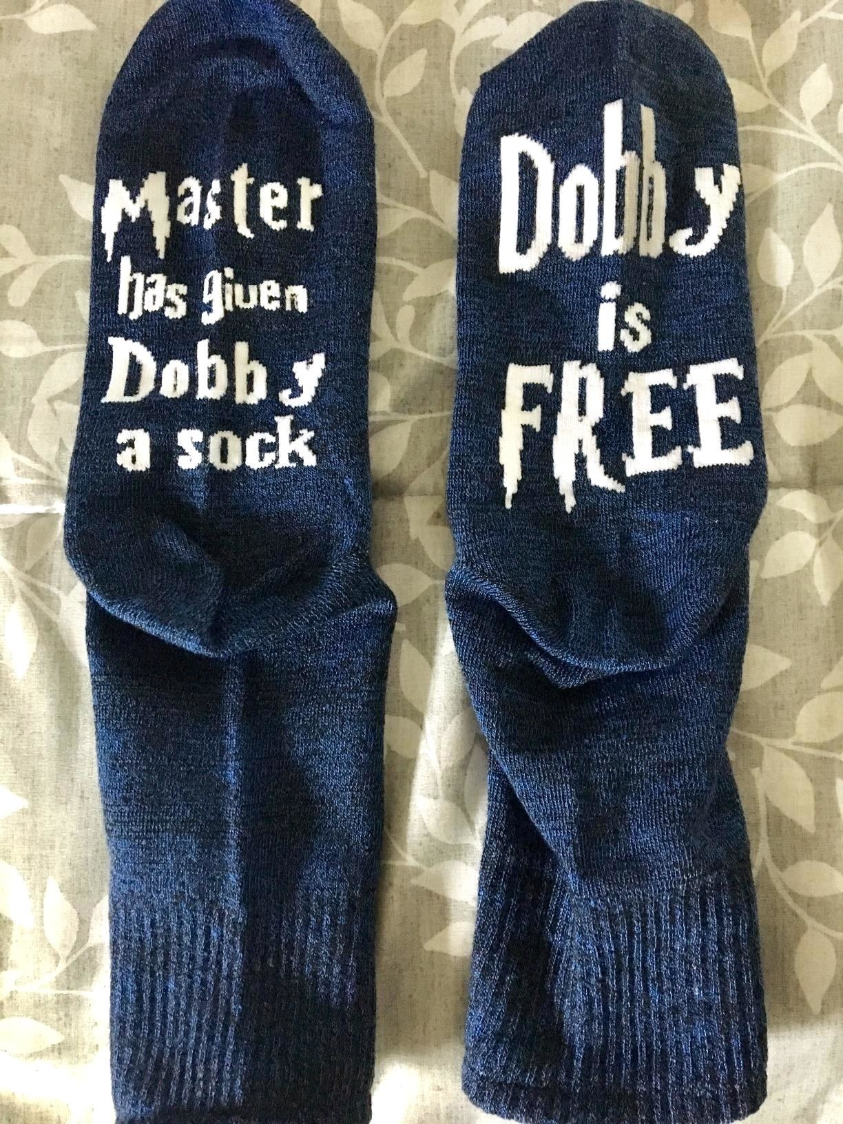 A reviewer&#x27;s pair of socks; one says &quot;Master has given Dobby a sock&quot; and the other &quot;Dobby is FREE&quot;, both in the Harry Potter font