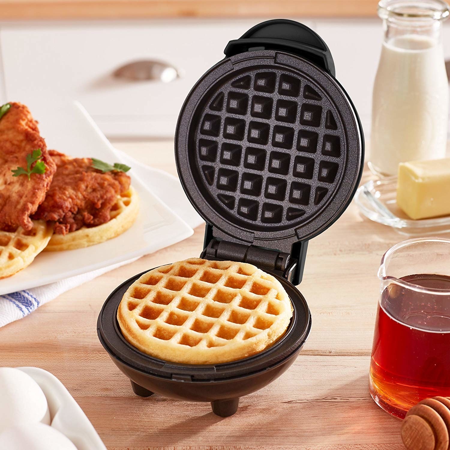 A mini waffle maker on a wooden table with a cooked waffle inside