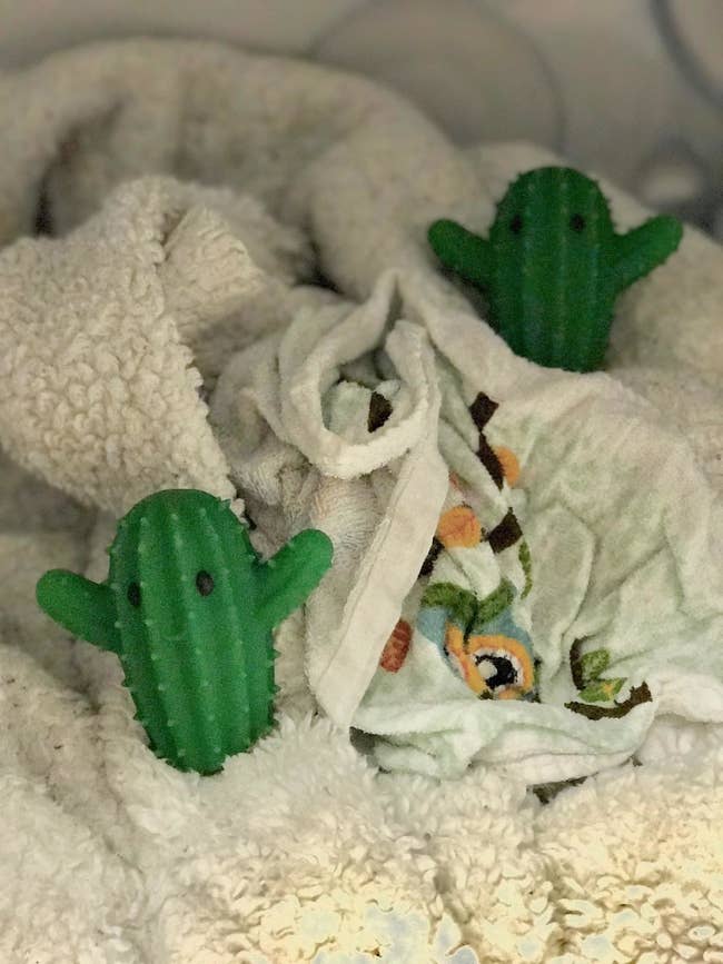 reviewer's two green cactus-shaped dryer balls on top of dry blankets