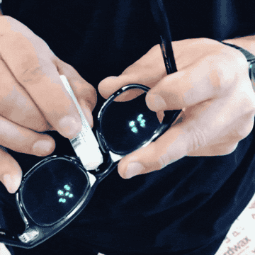 A GIF a person applying a stick of wax onto their glasses