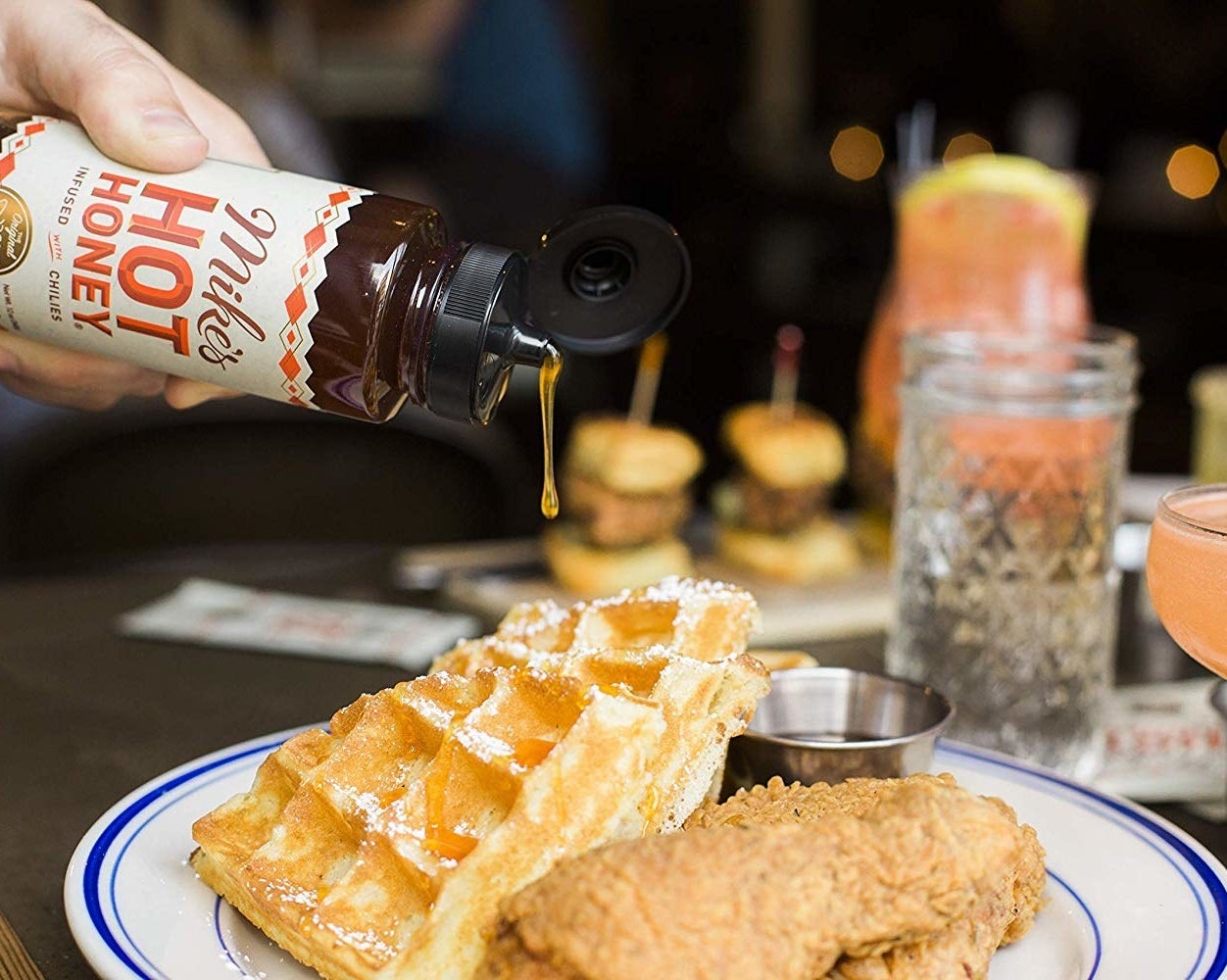 hot honey being squeezed onto chicken and waffles