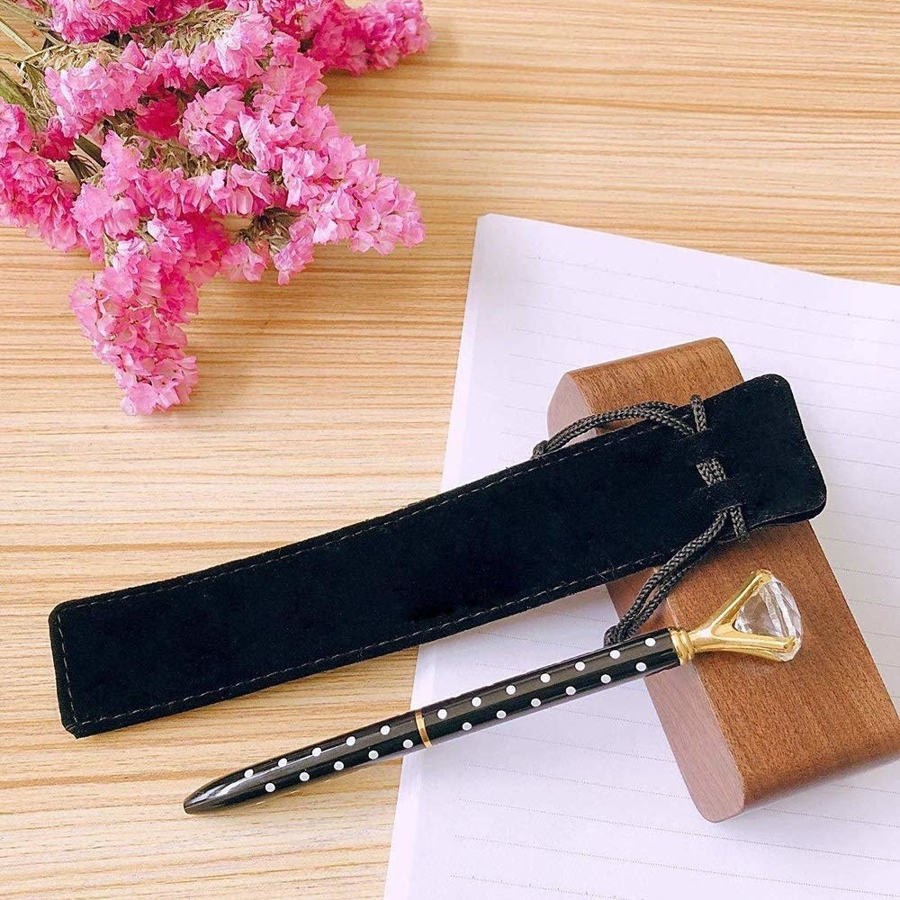 A pen with a diamond at the end next to a small velvet pouch