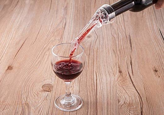The clear spout on top of a wine bottle being poured into a glass