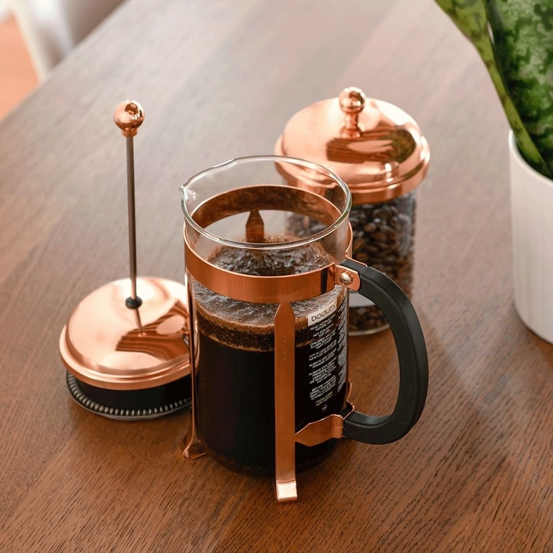 The filled french press beside a jar of beans