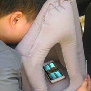person watching a movie from their phone inside the pillow 