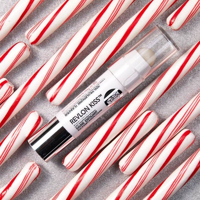 A tube of exfoliating lip balm surrounded by candy canes