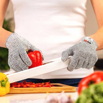 a reviewer using the gloves to slice a pepper on a mandolin