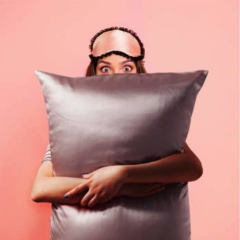 a model hugging a satin covered pillow