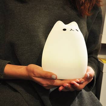 model holding the white cat-shaped lamp