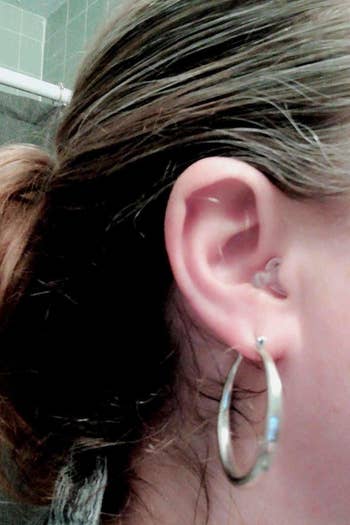 A close-up of it in a reviewer's ear; the clear tail very nearly blends in