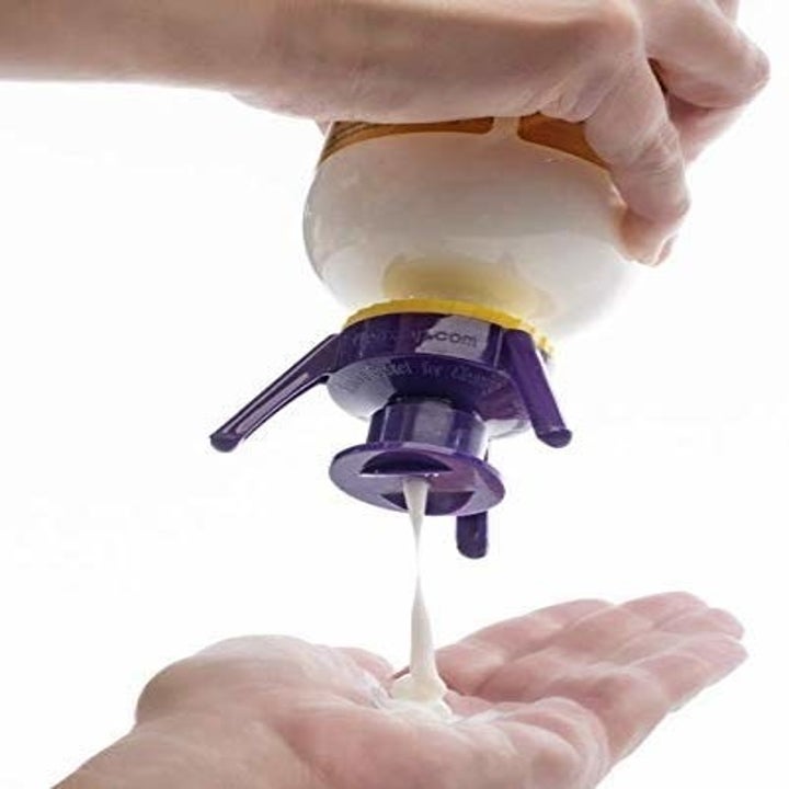 hands squeezing product out of the pop-top, which has three prongs so the bottle can balance upside-down