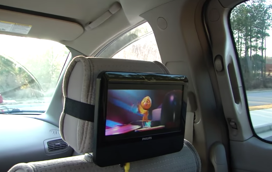 A portable DVD player attached to the back of a car seat playing a movie