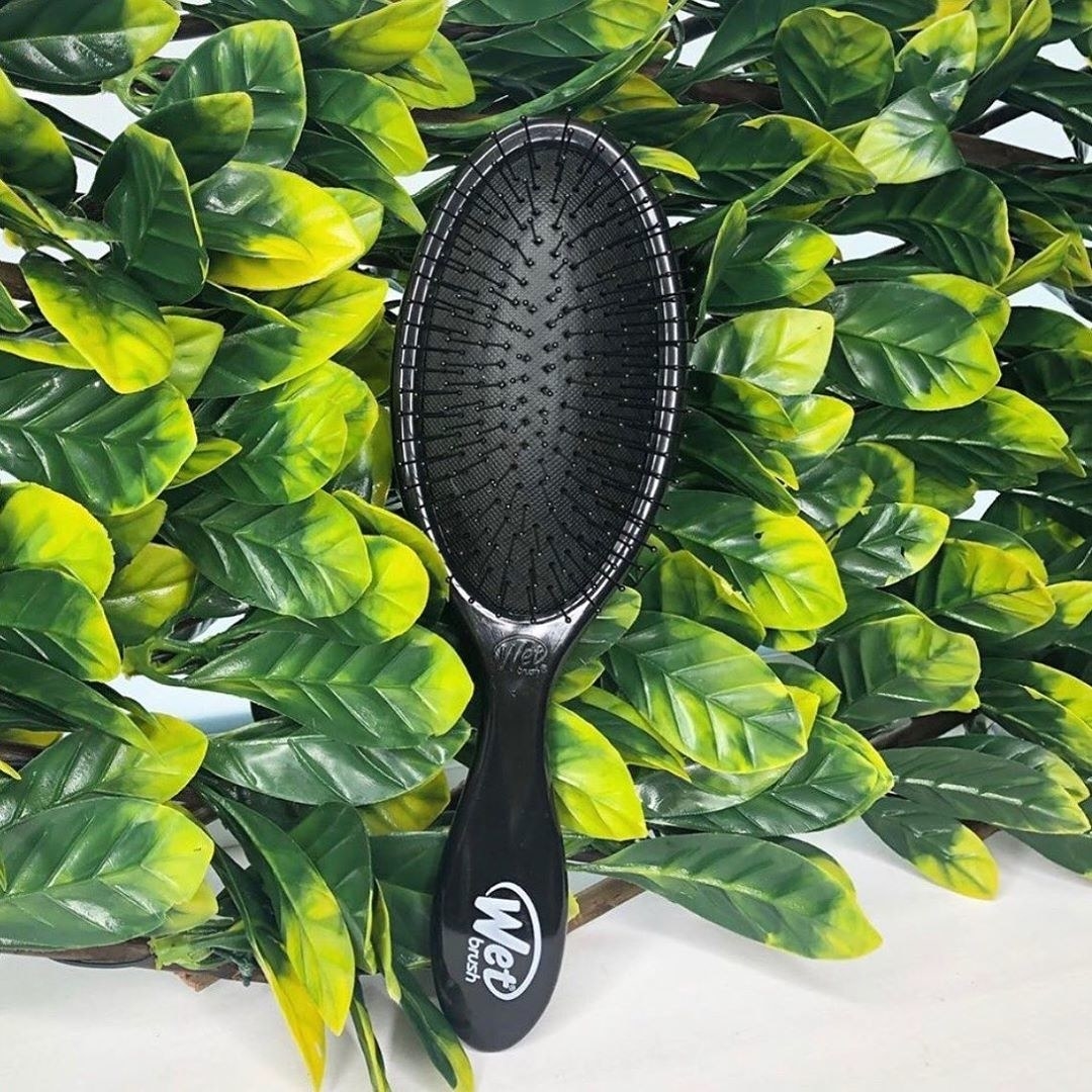 A WetBrush sitting on faux plant leaves