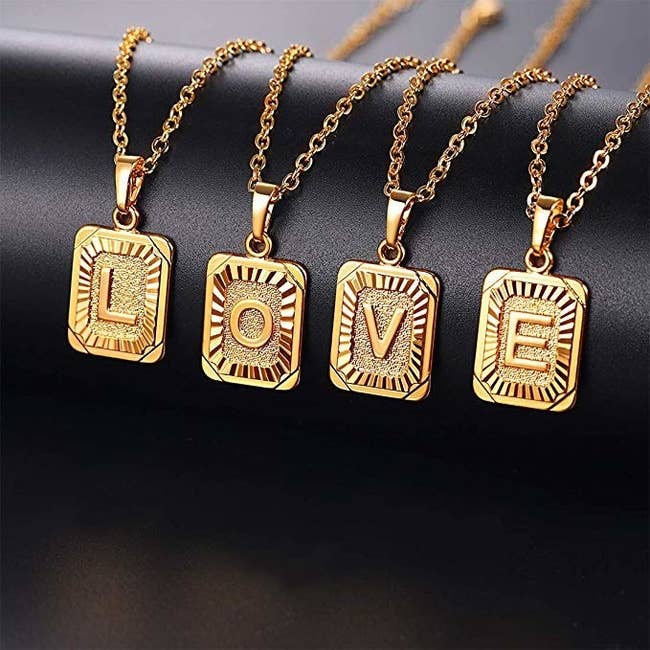 Four gold rectangle pendants on chains with the letters 'L, O, V, E' on them