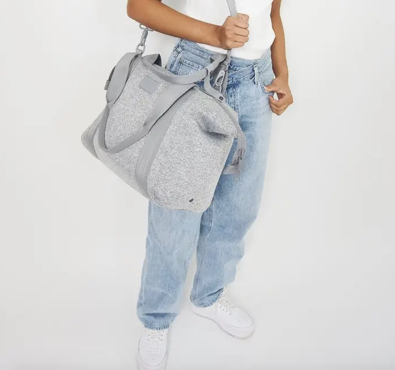 Model with the long strap of their shoulder and the square-shaped duffle in grey with shorter straps