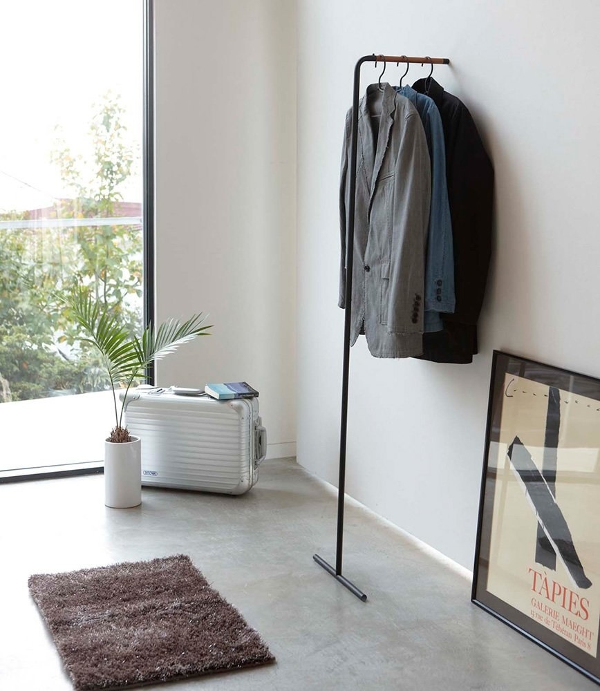 Free-standing coat rack with three jackets hanging on it 