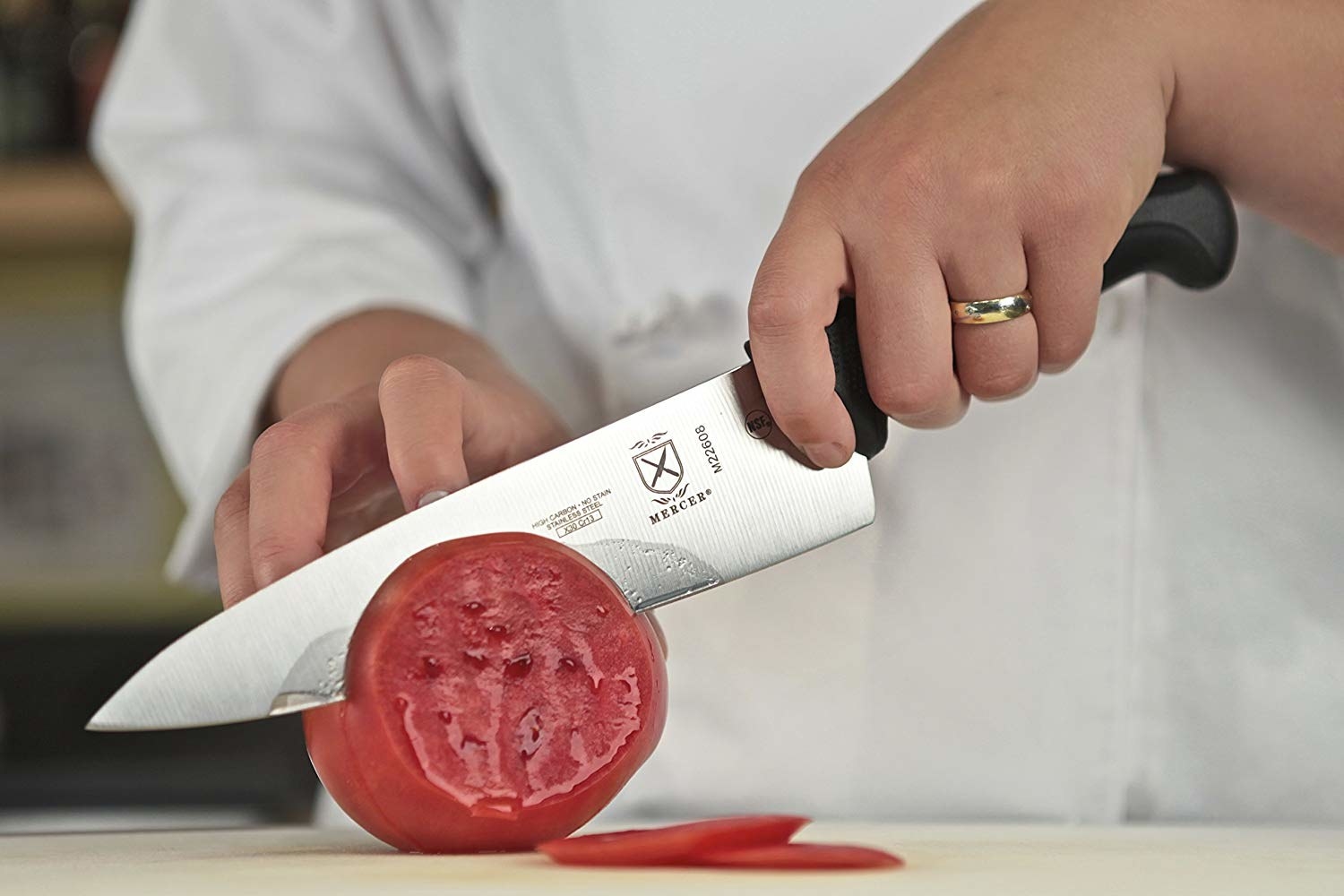 person using the knife to thinly slice a tomato