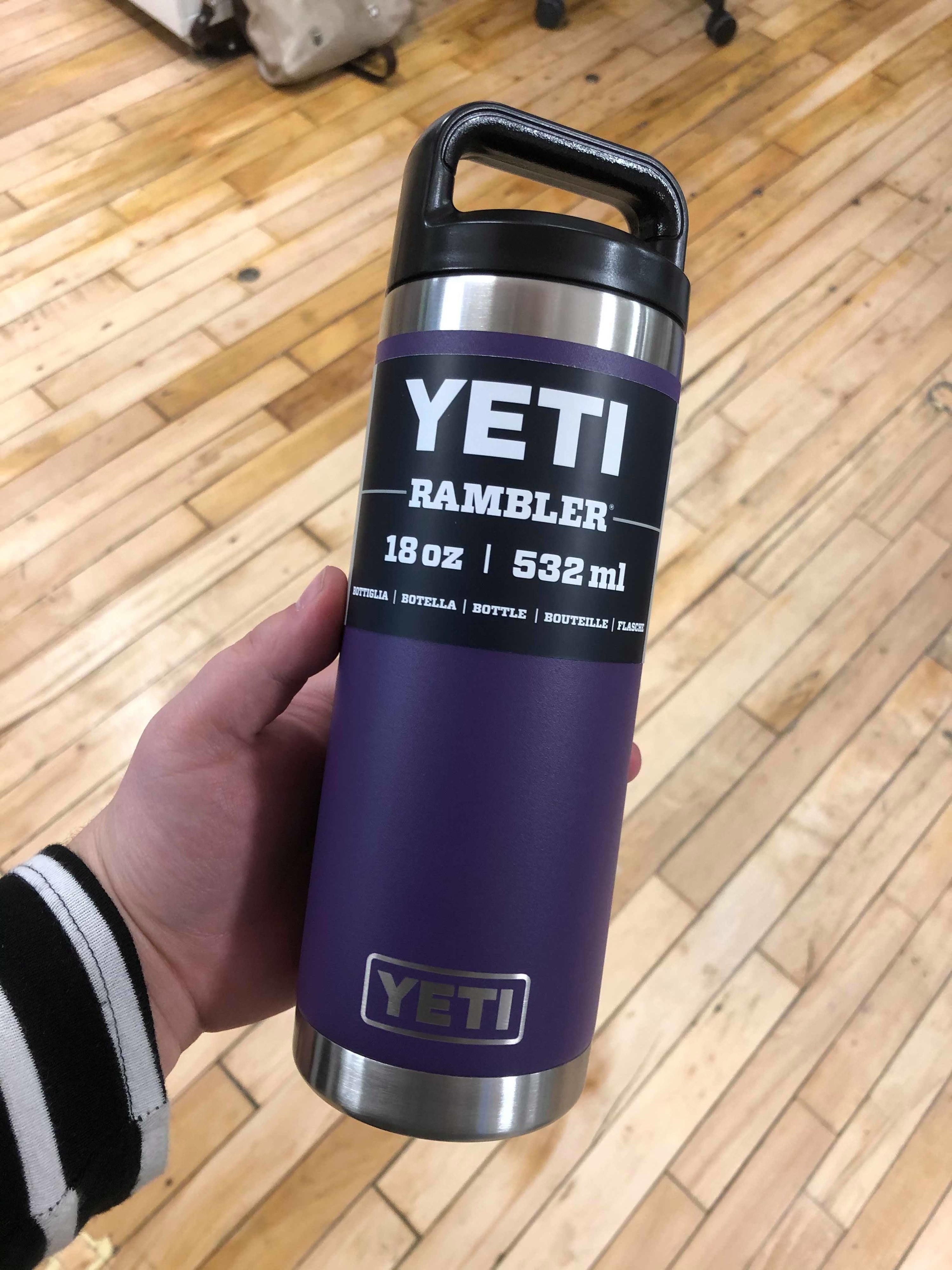 A person holding the Yeti mug over a hardwood floor