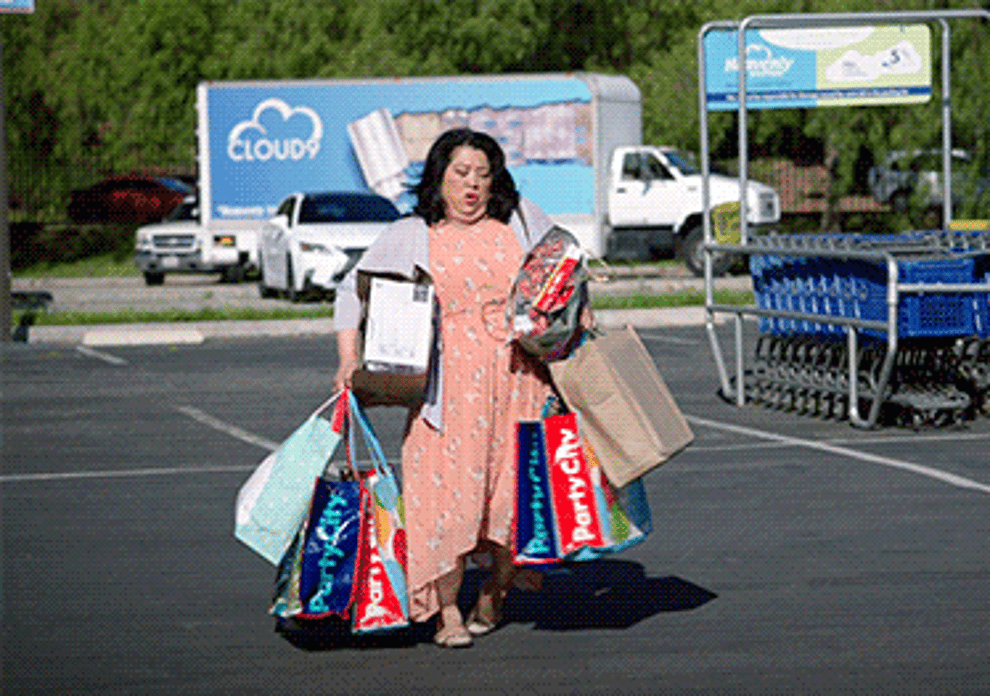 Gif of woman from Superstore carrying handfuls of bags that are falling from her arms 