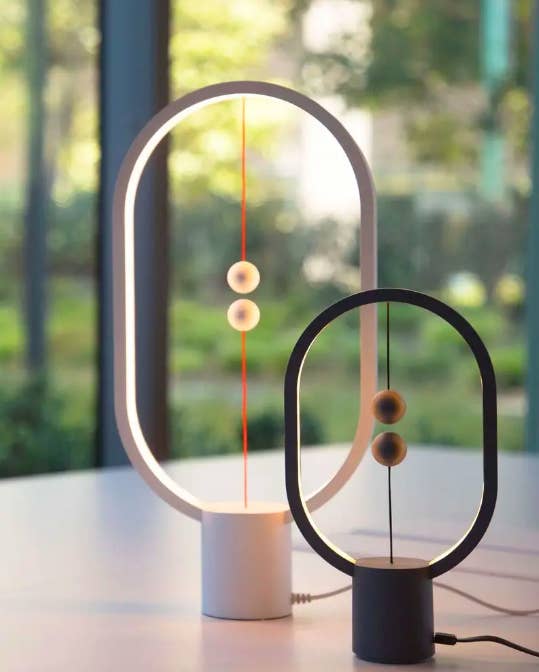 Oval light rings with center base and two magnetic balls attached to strings on top and bottom of light 