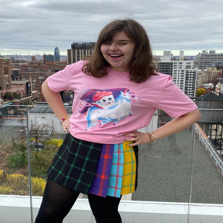 buzzfeed shopping editor wearing the pink T-shirt with Cuppy the cupcake riding a unicorn on it 