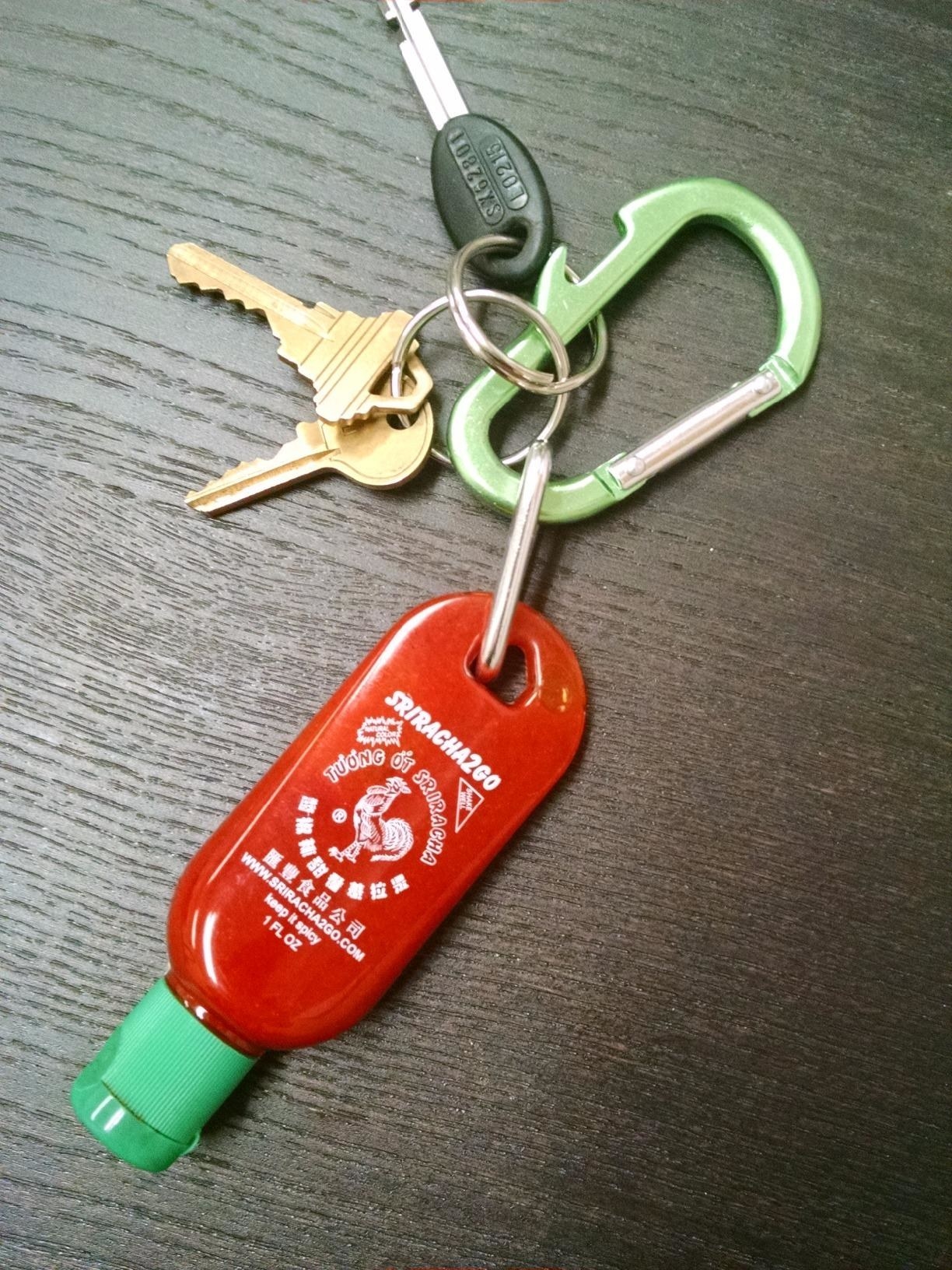 Red Sriracha key chain with a green cap