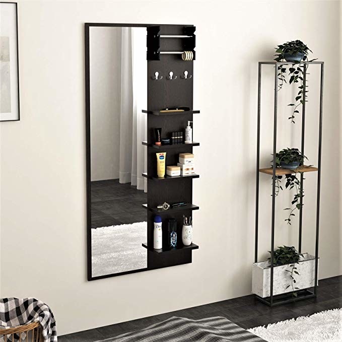 A tall mirror with shelves on it sides, holding cosmetics and toiletries