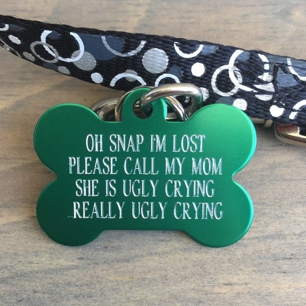 a green bone-shaped dog tag that says &quot;oh snap i&#x27;m lost please call my mom she is ugly crying really ugly crying&quot;